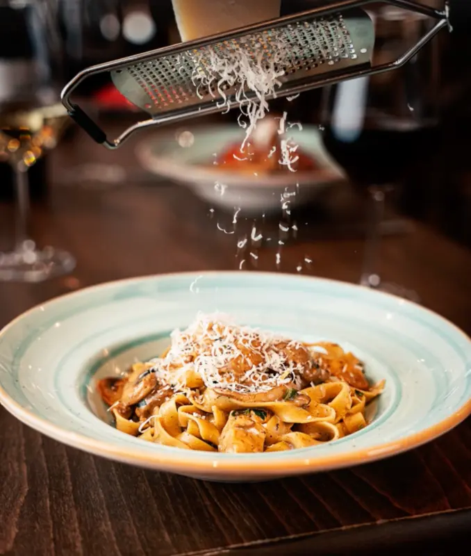 Freshly grated cheese being added to pasta at La Divina
